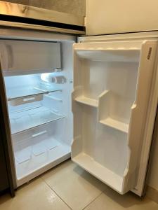 an empty refrigerator with its door open in a kitchen at Studio neuf avec acces piscine in Valergues