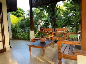 un patio con panche di legno, un tavolo e una pianta di Casa Chalé dos Pássaros Guarajuba a Camassari