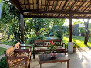 a patio with benches and a table with a potted plant at Casa Chalé dos Pássaros Guarajuba in Camacari