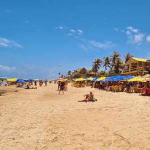 un groupe de personnes sur une plage avec des parasols dans l'établissement Apartamento de descanso com a brisa do Mar!, à Lauro de Freitas 16 autres photos