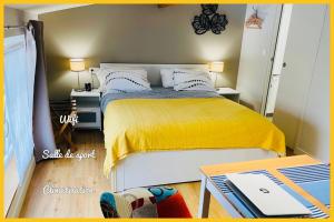 a small bedroom with a bed with a yellow blanket at Les Gîtes du Domaine de Ludeye in Listrac-Médoc