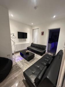 a living room with black leather furniture and a flat screen tv at Large 6 Bed 6 Bathroom House - Ideal For Families, Large Groups, Contractors & Business Travellers in Watford
