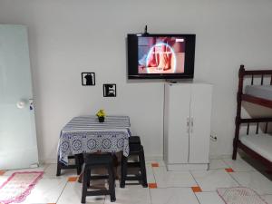 a dining room with a table and a tv on a wall at Residencial Caiobá II in Matinhos
