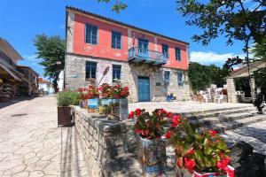 a house with flowers in front of a stone wall at Afitos Guest House in Afitos