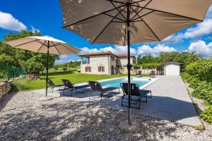 a patio with chairs and umbrellas next to a pool at Old Stone Villa Katarina in Nedeščina