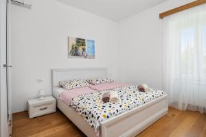 a white bedroom with a bed with pink and white sheets at Old Stone Villa Katarina in Nedeščina