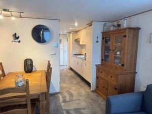 a kitchen and dining room with a table and a blue couch at Chalet op Ameland voor 5 personen in Buren +6 photos
