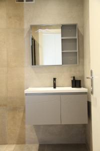 a bathroom with a white sink and a mirror at Pirgos Cozy Apartment for 4 by MPS in Pyrgos