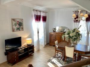 Una sala de estar con una mesa y un televisor. en La Maison Marguerite, en Herrère