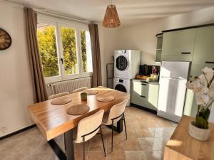 a kitchen with a wooden table with chairs and a refrigerator at Hellébore - Cosy avec garage in Saint-Claude