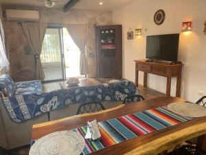 a living room with a couch and a tv at SandyToes La Casita del Mexicano in Celestún