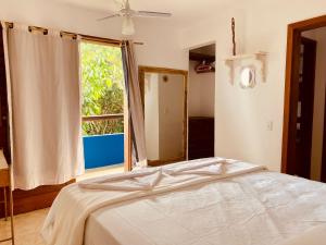 ein Schlafzimmer mit einem Bett und einem großen Fenster in der Unterkunft Bromélia Blue in Itacaré + 43 Fotos