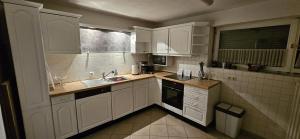 eine Küche mit weißen Schränken, einer Spüle und einem Fenster in der Unterkunft Whole Apartment Marechal near zurich airport free Parking Wifi in Hohentengen