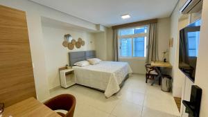 una camera da letto con un letto e un tavolo in una stanza di Nô Centro Suítes 3 - Apto moderno com cozinha compartilhada a Florianópolis