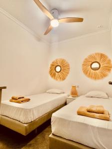 2 letti in una camera con ventilatore a soffitto e specchi di La Primera de Occidente a Cadice