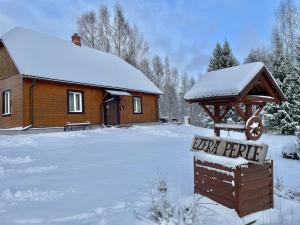 a house with a sign in the snow at Ezera Pērle in Ķeipene