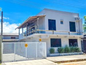 una casa blanca con una valla delante en Residencial da Bia - Casas com 2 Dorms na Praia da Cal com Piscina Térmica, en Torres