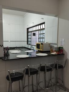 a kitchen with a counter with three bar stools at Casa Presidente Venceslau in Presidente Venceslau