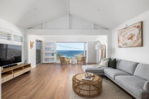 un salon avec un canapé et une table dans l'établissement Waves at Boat Harbour, 65 Kingsley Dr - stunning house, fantastic waterviews and dog friendly, à Boat Harbour