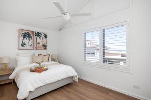 une chambre blanche avec un lit et une fenêtre dans l'établissement Waves at Boat Harbour, 65 Kingsley Dr - stunning house, fantastic waterviews and dog friendly, à Boat Harbour