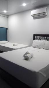 a white bedroom with two beds and a light at Okawango Hotel in Girardot