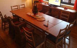 a dining room table with chairs and a television at Cottage House in Stožec +38 photos