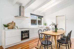 cocina blanca con mesa de madera y sillas en Quiet & Cozy 4 Bedroom Home, en Norlane