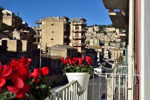 a view of a city from a balcony with red flowers at La Casetta Bianca in Modica