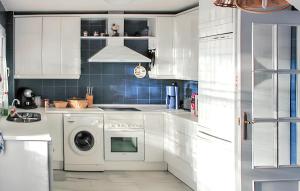 a kitchen with white cabinets and a washing machine at Elegant Villa in Nuevo Portil with Shared Pool in El Portil