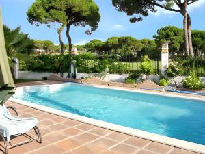 a swimming pool with a chair next to it at Elegant Villa in Nuevo Portil with Shared Pool in El Portil