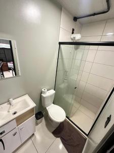 a bathroom with a shower and a toilet and a sink at Pousada e Lofts Jardim C in Jaú