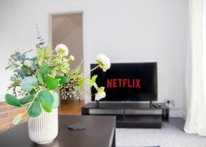 a living room with a tv and a vase with flowers at Parkside House Stevenage in Stevenage