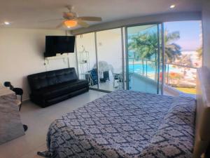 a bedroom with a bed and a couch and a balcony at Aria Ocean Beachfront Condos in Nuevo Vallarta