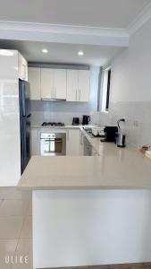 Una cocina con gabinetes blancos y encimera. en Modern 2 Bedroom Apartment with Parking Central Parramatta, en Sídney 4 fotos más