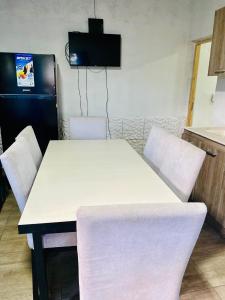 Una mesa blanca y sillas en una cocina con nevera. en Alquiler, en Colonia Las Rosas