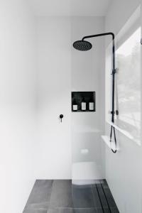 La salle de bains blanche est pourvue d'une porte de douche en verre. dans l'établissement Love - Denmark WA, à Denmark