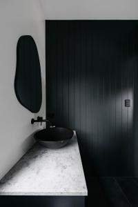 une salle de bain noire avec un lavabo et un miroir dans l'établissement Love - Denmark WA, à Denmark 86 autres photos