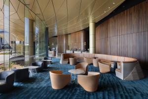 a lobby with tables and chairs in a building at Pullman Auckland Airport in Auckland