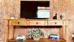 a television on top of a wooden table with books at Casa temporada Ilhabela in Ilhabela