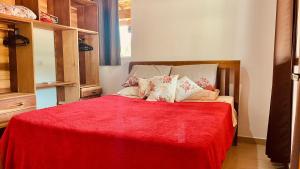 a bedroom with a bed with a red blanket at Casa temporada Ilhabela in Ilhabela