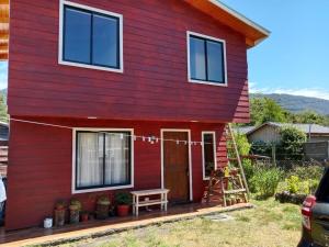Una casa roja con un banco afuera. en Cabaña familiar Doris, en Coñaripe 15 fotos más