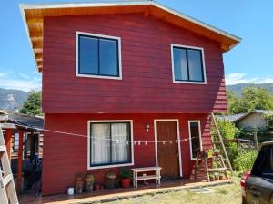 una casa roja con una cuerda delante de ella en Cabaña familiar Doris, en Coñaripe