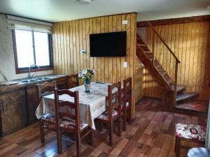 a dining room with a table with chairs and a television at Cabaña familiar Doris in Coñaripe