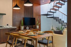 a dining room with a table and chairs and a staircase at Raya Villa by Betterplace in Canggu