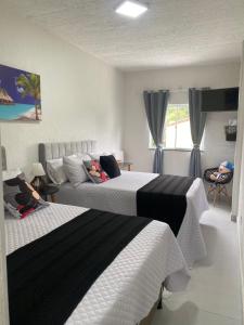 a bedroom with two beds and a window at MAHALO 1004 Suites in Maricá