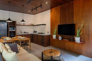 a kitchen and living room with a couch and a tv at Raya Villa by Betterplace in Canggu