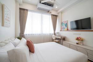 Una habitación de hotel con una cama blanca y un televisor. en 4BR Walk to Chinatown, MRT Luggage Dropoff, en Bangkok