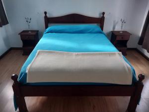 a bedroom with a bed with blue sheets and two tables at Big House in Merlo