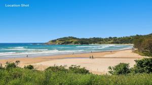 - une plage avec des personnes se promenant sur le sable et l'océan dans l'établissement Tidal Nook, à Coffs Harbour