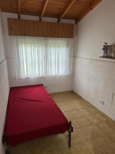 ein rotes Bett in einem Zimmer mit Fenster in der Unterkunft Casa playa Valeria in Valeria del Mar